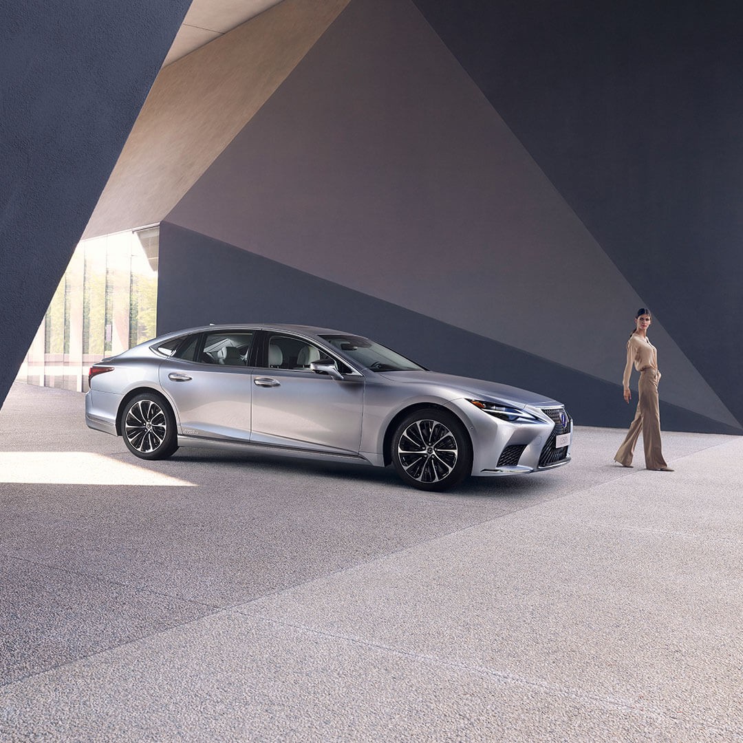 A woman standing next to a Lexus LS