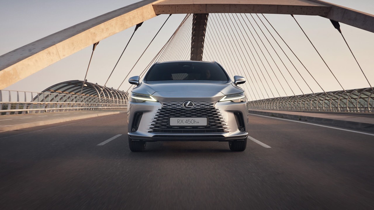 Front view of the Lexus RX 450h+ driving over a bridge